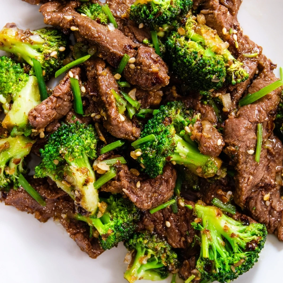 A close-up of Keto Friendly Beef and Broccoli Stir Fry with tender beef and bright green broccoli coated in glossy sauce, served on a white plate.