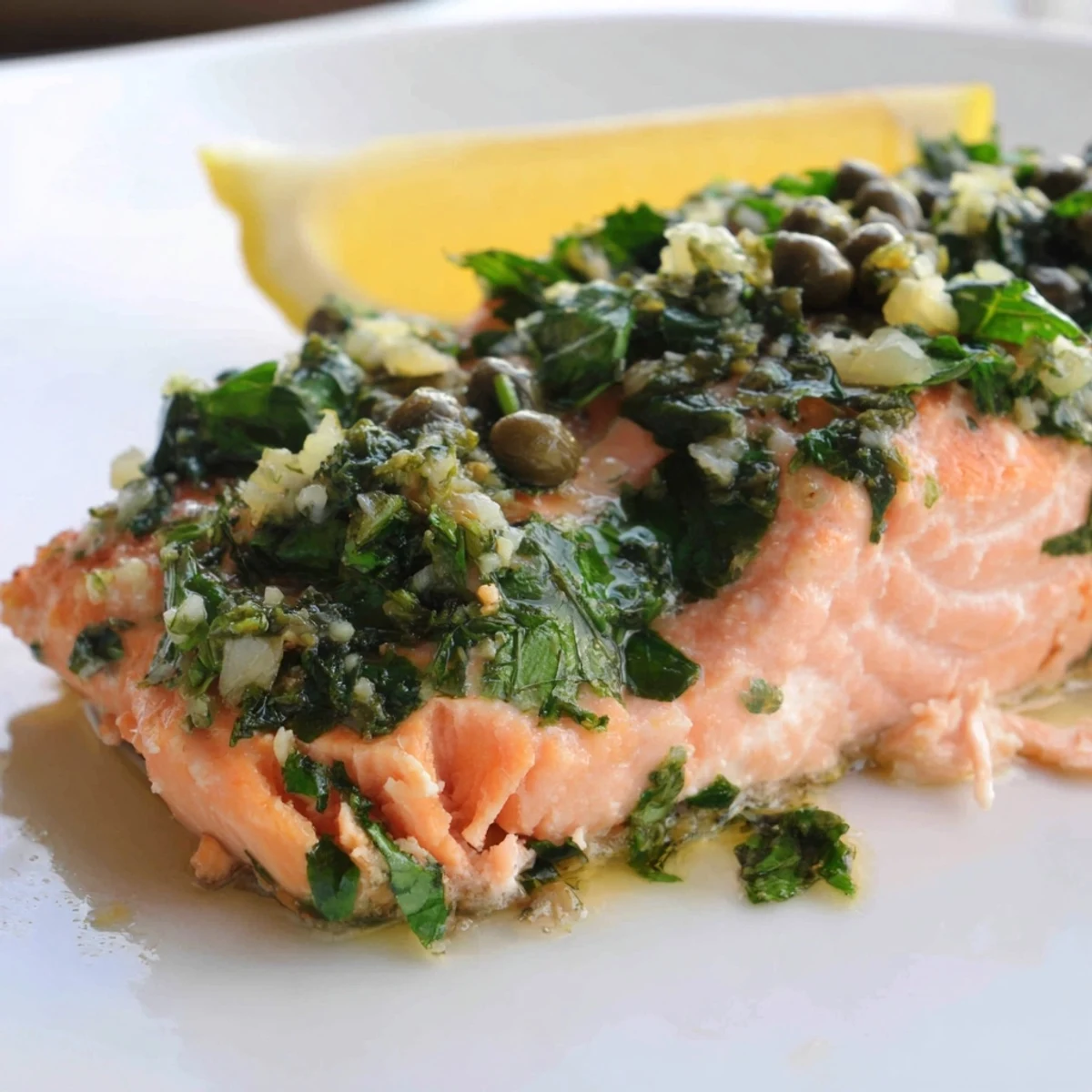 Freshly prepared salsa verde with herbs and capers spooned over tender oven-baked salmon fillets.