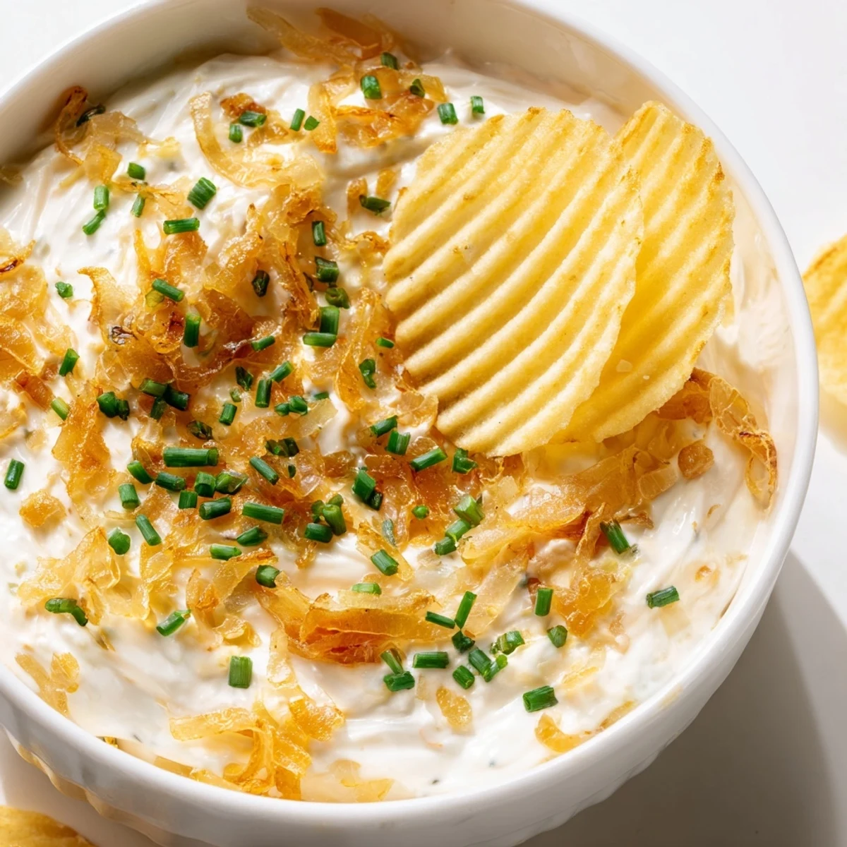 Warm, savory Game Day Onion Dip surrounded by crunchy potato chips on a platter, ready for easy snacking during a football viewing party.