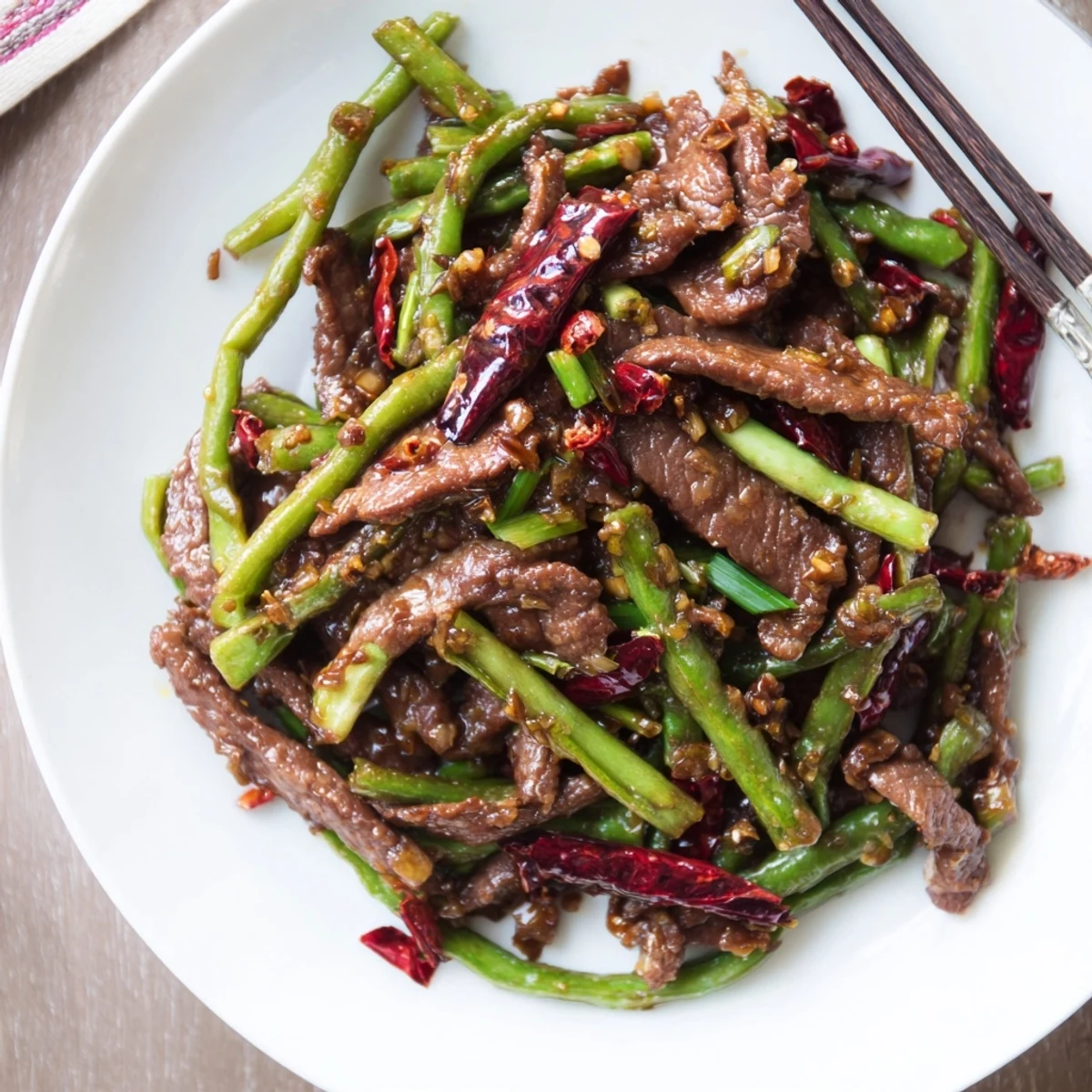 A close-up showcases the glossy, fiery glaze coating tender beef and blistered beans, perfect over steamed jasmine rice.