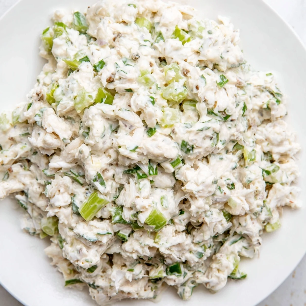 Creamy remoulade sauce with crab meat garnished with fresh parsley, served as a zesty dip with crackers.