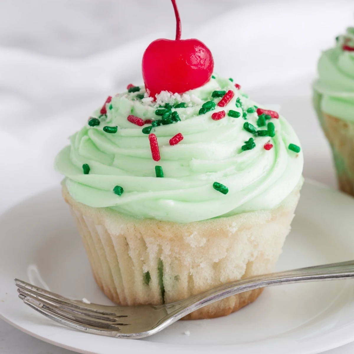 Freshly baked Shamrock Shake Cupcakes with light green frosting, arranged on a cooling rack next to a glass of milk.
