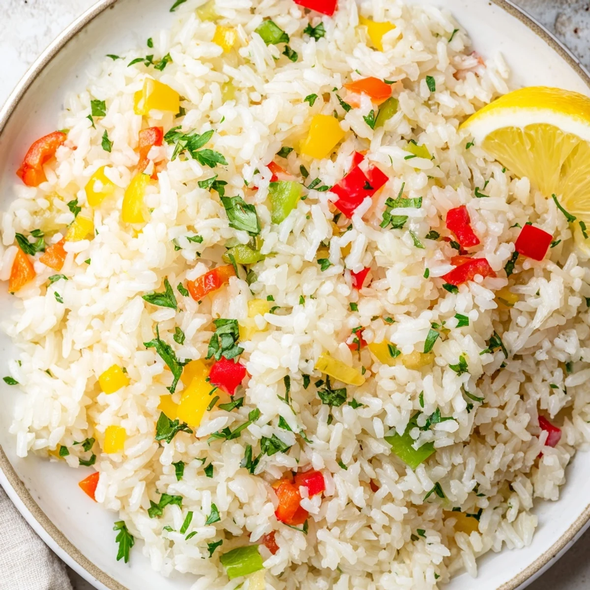 Freshly cooked Rice Pilaf with Peppers and Onions is garnished with chopped parsley and served with lemon wedges on the side for a bright, Mediterranean flavor.
