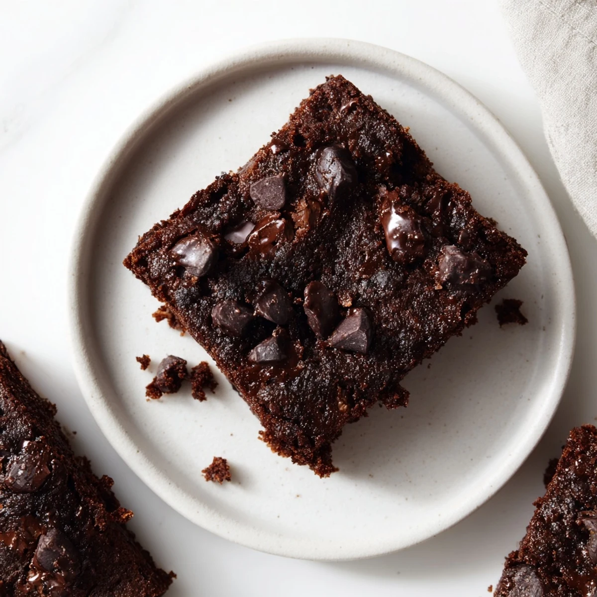 Gluten-Free Almond Flour Brownies stacked on a white plate with a glass of milk for a classic dessert pairing.