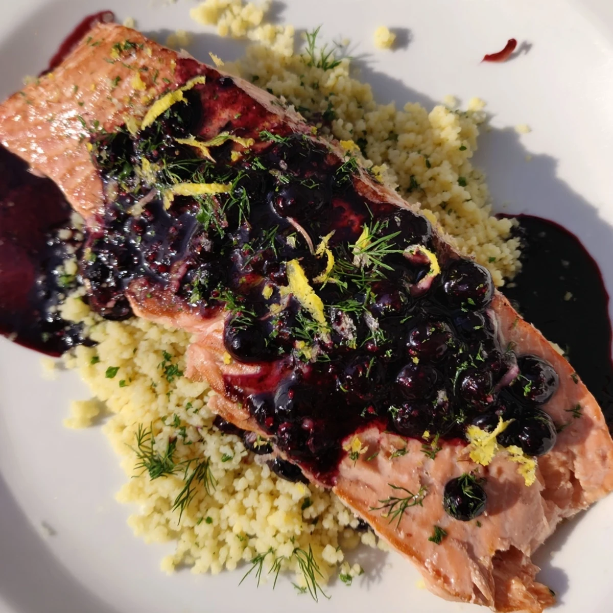 A close view of Blueberry Glazed Salmon with Lemon Herb Couscous, flaky fish and citrus couscous ready to serve.