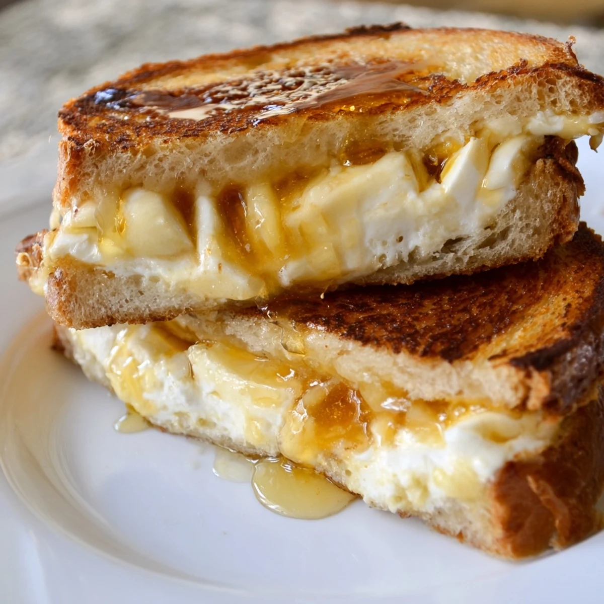 The cheese grilled cheese with honey bliss sits on a wooden board, cut in half to reveal the gooey cheese pull and golden crust.