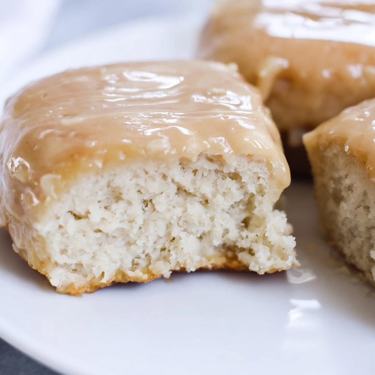 Freshly fried Maple Donut Bars with a glossy, rich maple glaze stacked on a wire cooling rack.  