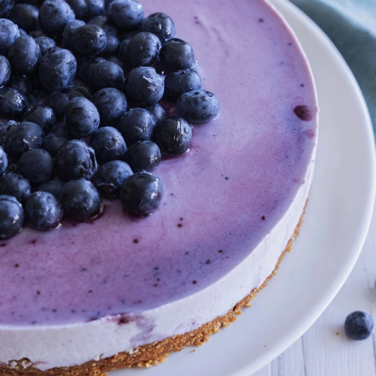 Blueberry Mousse Cheesecake displayed with fresh berries and a mint garnish on a rustic wooden table.