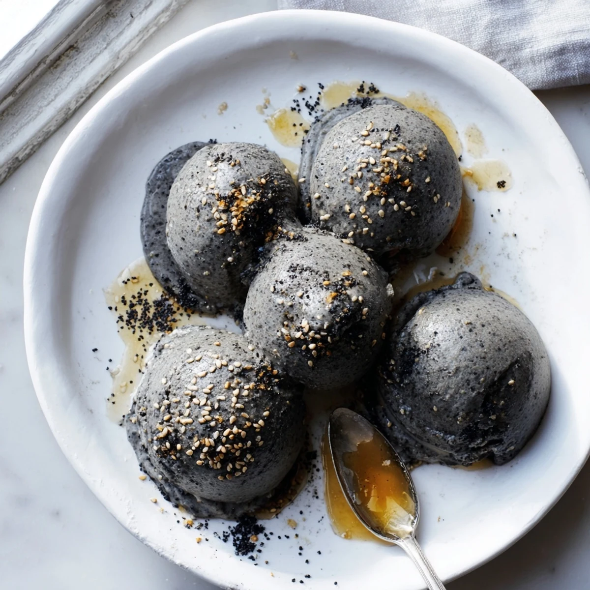 Rich and nutty Toasted Black Sesame Ice Cream paired with fresh berries on a chilled dessert plate.