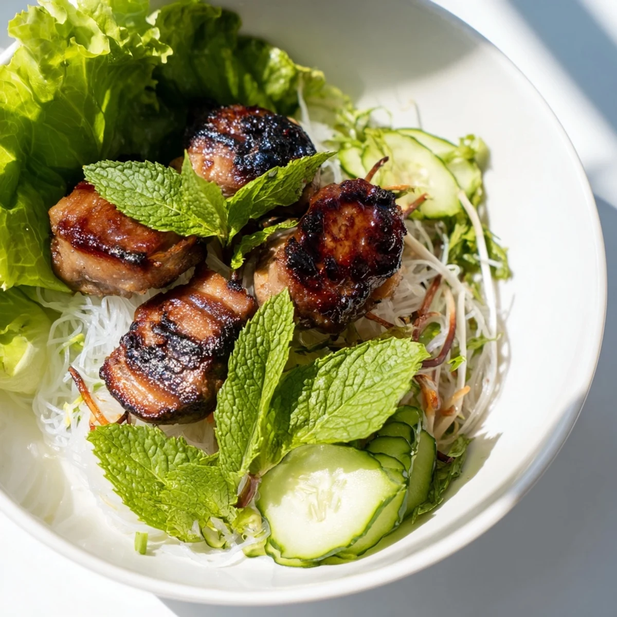 Sweet, smoky grilled pork from Bun Cha Hanoi is served with crisp lettuce and bean sprouts.