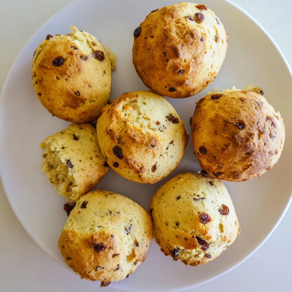 Freshly baked Irish Soda Bread Muffins rest on a wooden board, showcasing golden crusts and soft, crumbly centers.