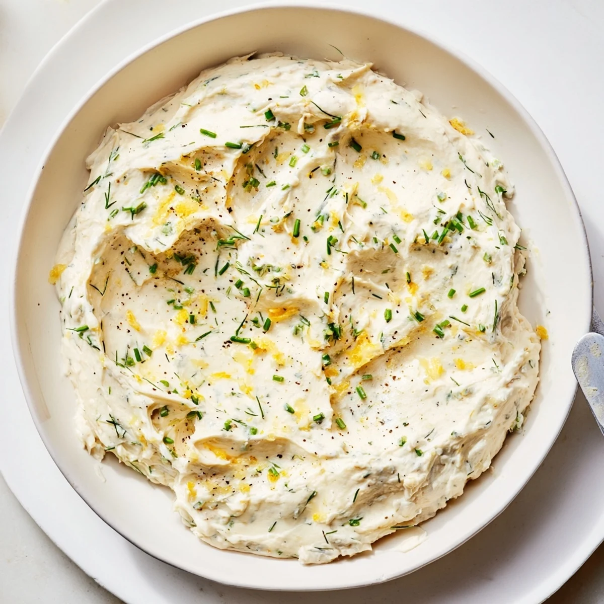 The Simple Easter Herb Cheese Dip in a rustic bowl surrounded by colorful vegetable sticks and crackers for serving.