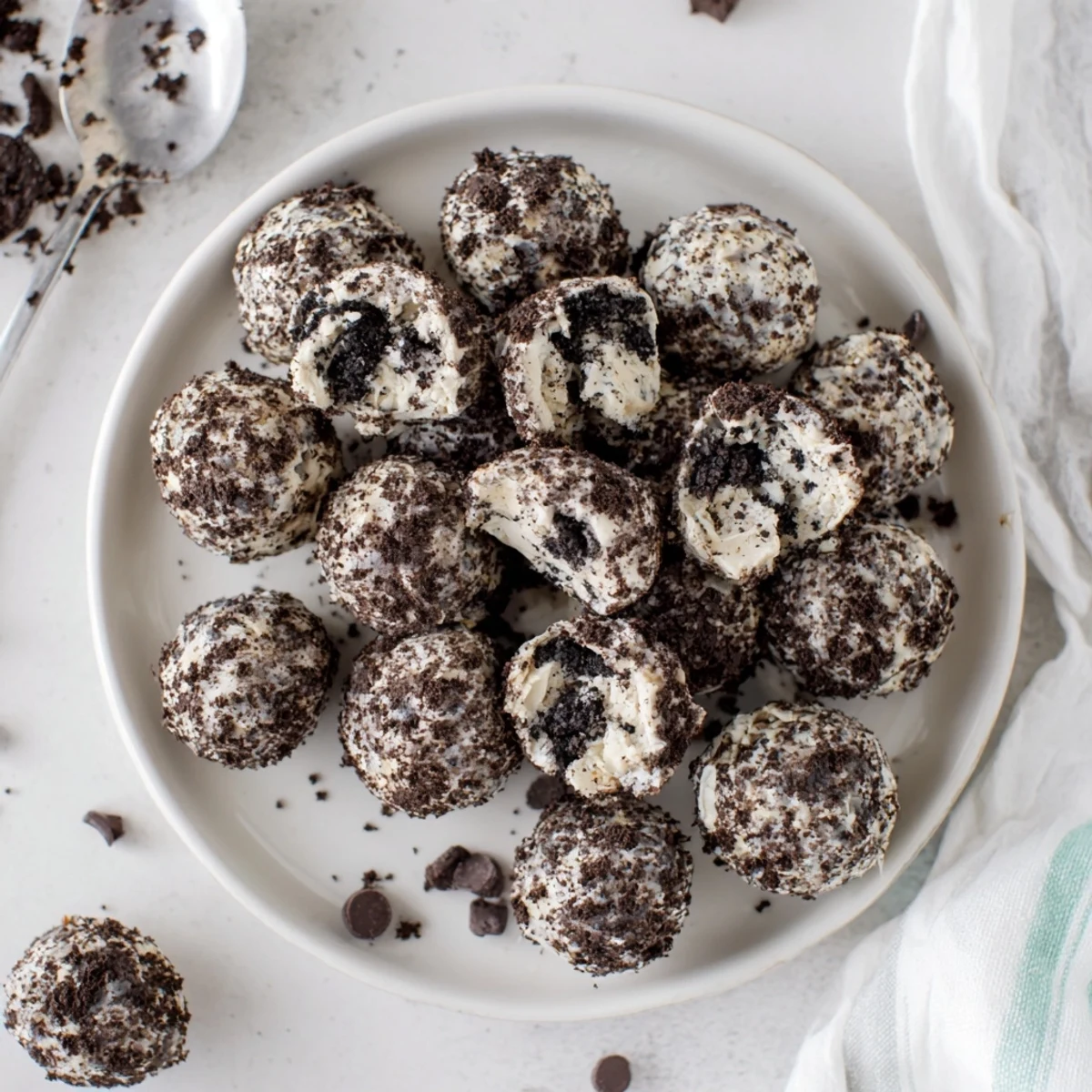 Cream Cheese Oreo Protein Balls sit on a tray with a drizzle of melted chocolate.