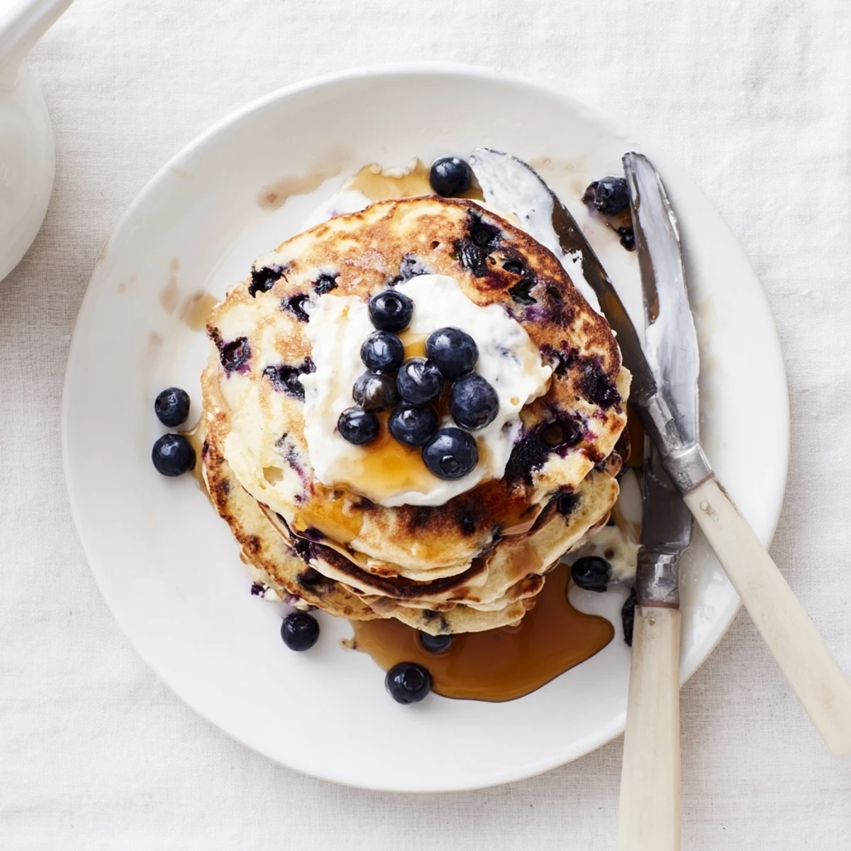 Golden Greek Yogurt Blueberry Pancakes sizzle on a griddle, showing juicy blueberry pockets and a soft, tangy crumb.