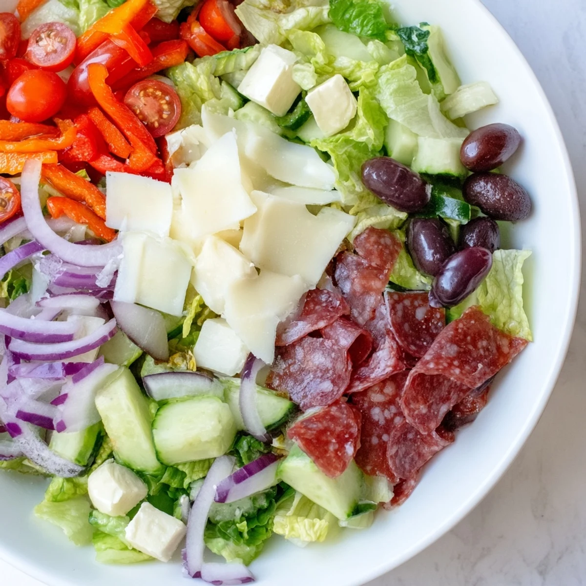 Fresh Italian Chopped Salad with cubed mozzarella, shaved Parmesan, roasted red peppers, and savory salami coated in homemade olive oil dressing