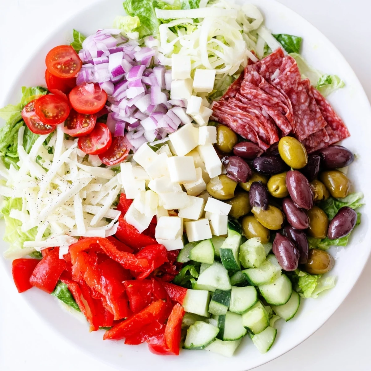 Vibrant bowl of Italian Chopped Salad featuring crisp romaine, cherry tomatoes, olives, pepperoncini, and Genoa salami tossed in tangy dressing