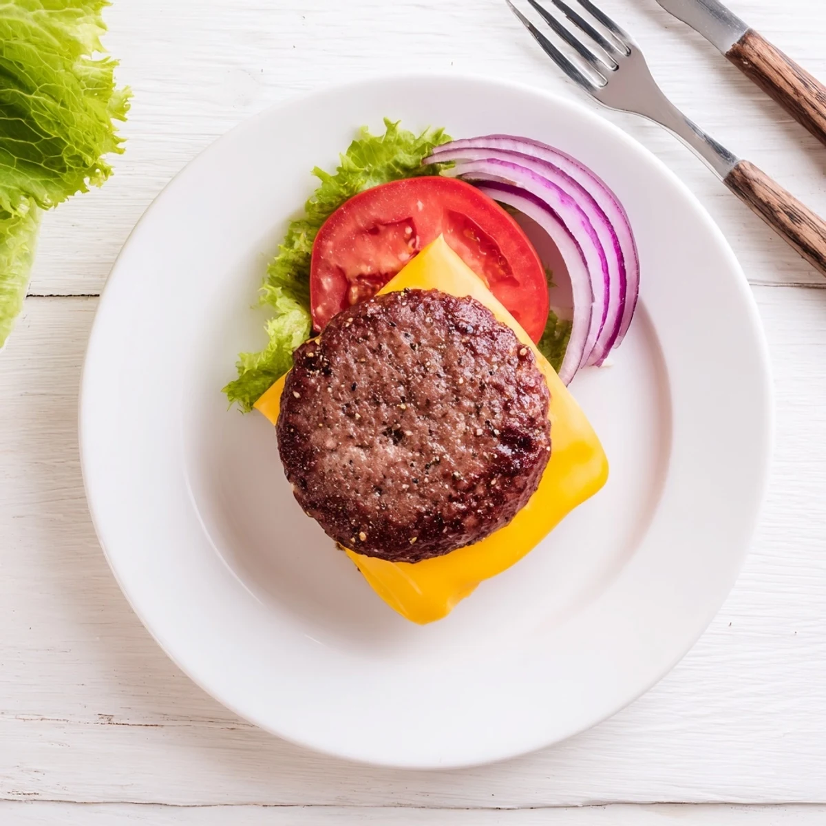 Juicy homemade hamburger patties sizzling in air fryer basket topped with melting cheddar and onion slices