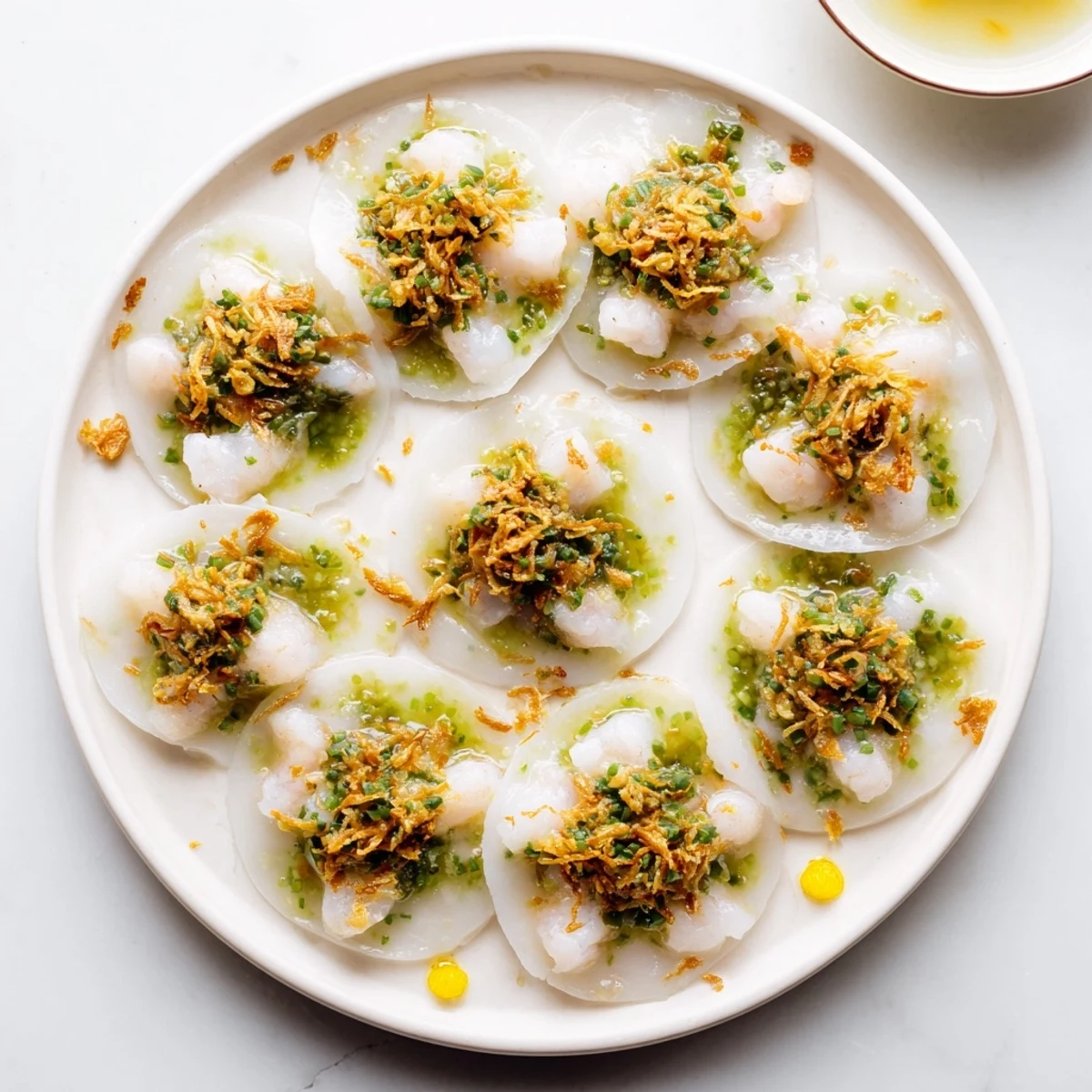 Delicate Vietnamese Banh Beo appetizer garnished with crispy fried shallots and bright red chili slices