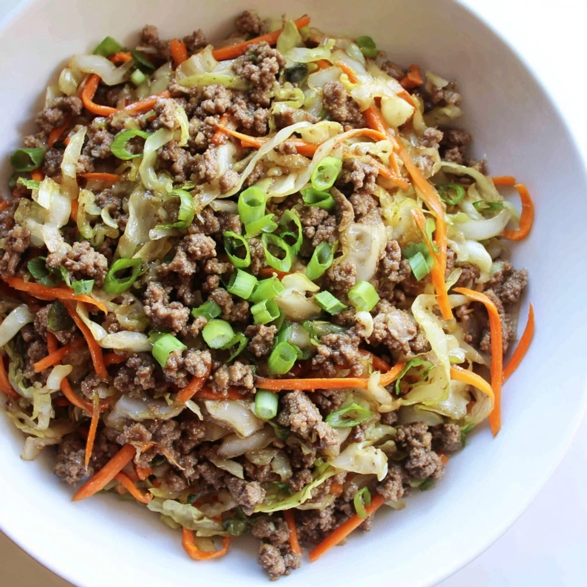 Hearty ground beef and cabbage stir fry plated with steamed rice and colorful shredded carrots