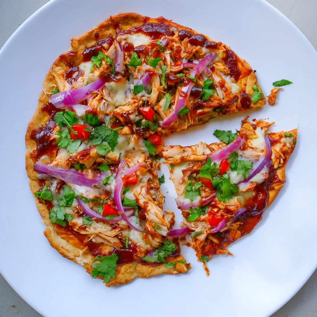 Golden homemade BBQ chicken pizza with bubbling melted cheese, red onions, and cilantro garnish on a crispy crust