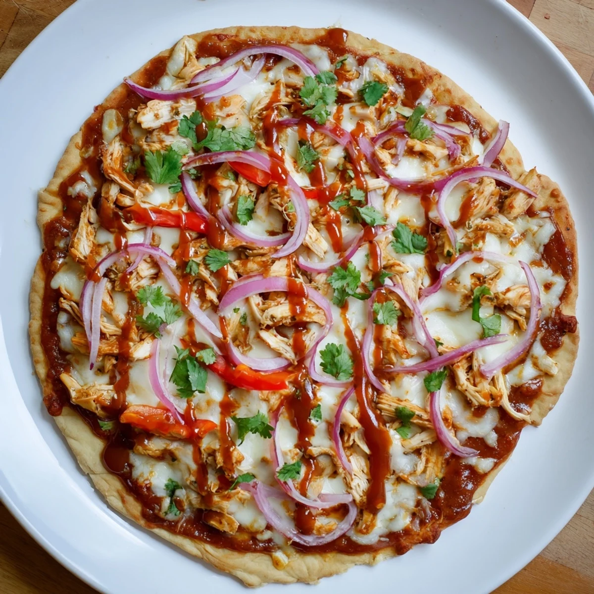 Sliced homemade BBQ chicken pizza revealing tender smoky chicken pieces and colorful bell peppers on a wooden board