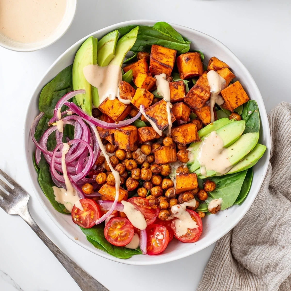 Nourishing sweet potato bowl arranged with tender roasted vegetables, chickpeas, and velvety tahini sauce
