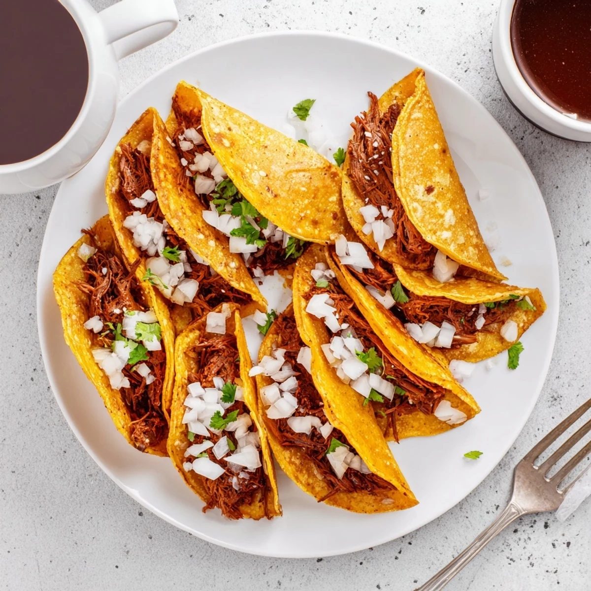 Delicious super crispy birria tacos garnished with fresh cilantro, onion, and lime