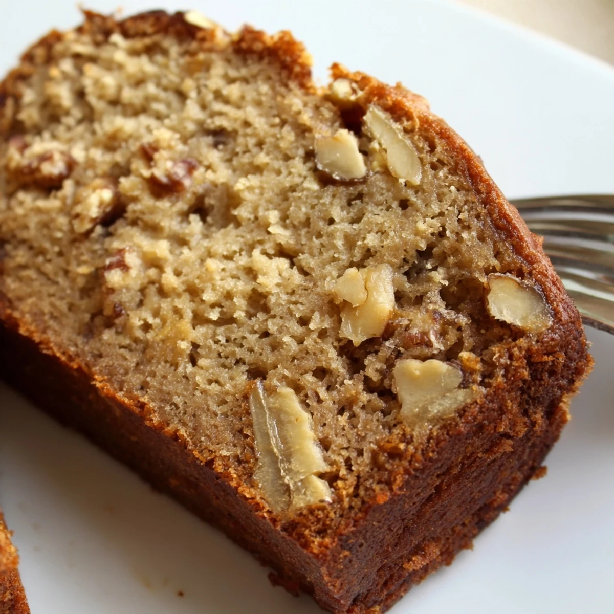 Slices of moist ultimate banana nut bread revealing the tender crumb and scattered nut pieces throughout