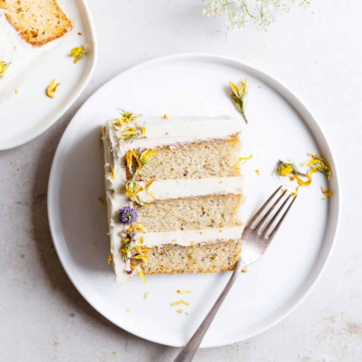 Elegant three-tier London Fog cake topped with edible flowers and zesty lemon garnish