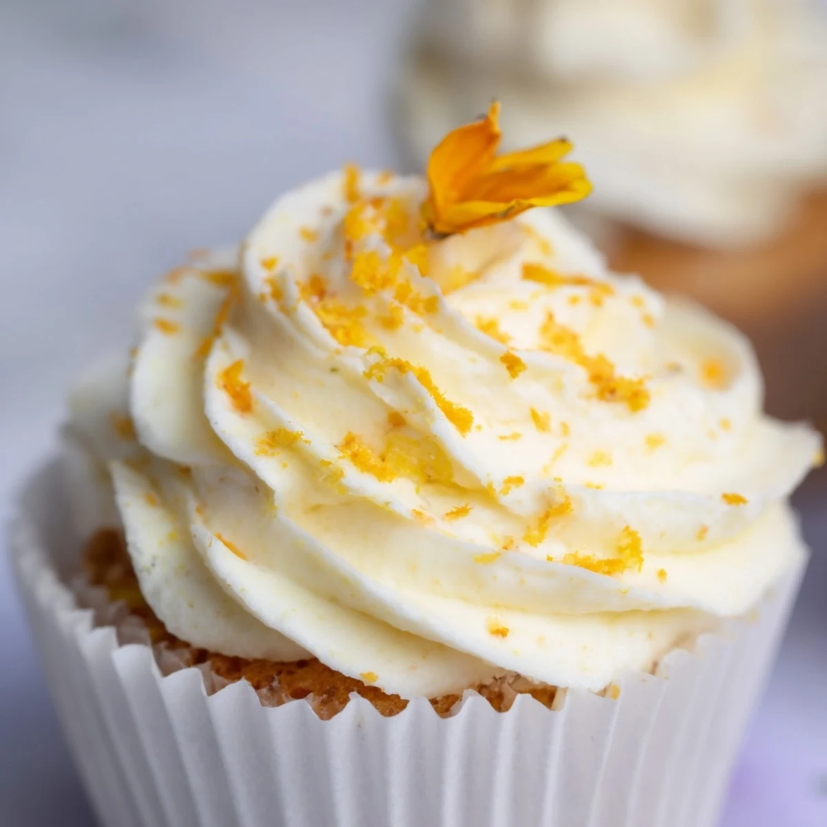 Golden orange blossom cupcakes topped with fluffy citrus frosting and garnished with fresh orange zest
