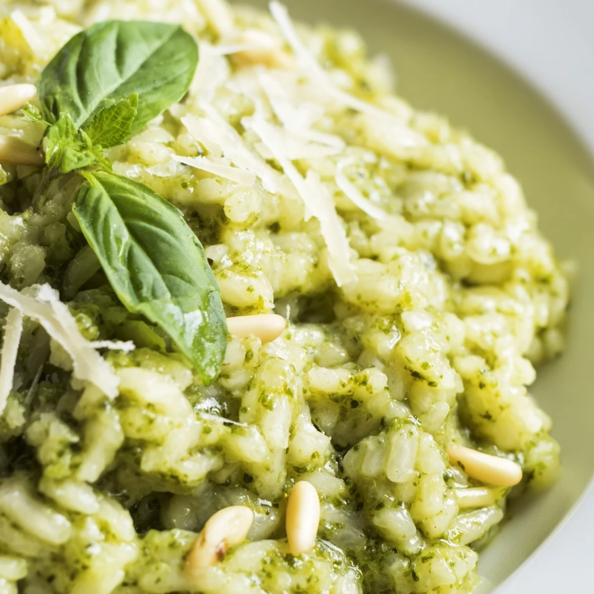 Steaming Italian Parmesan pesto risotto sprinkled with pine nuts and basil leaves