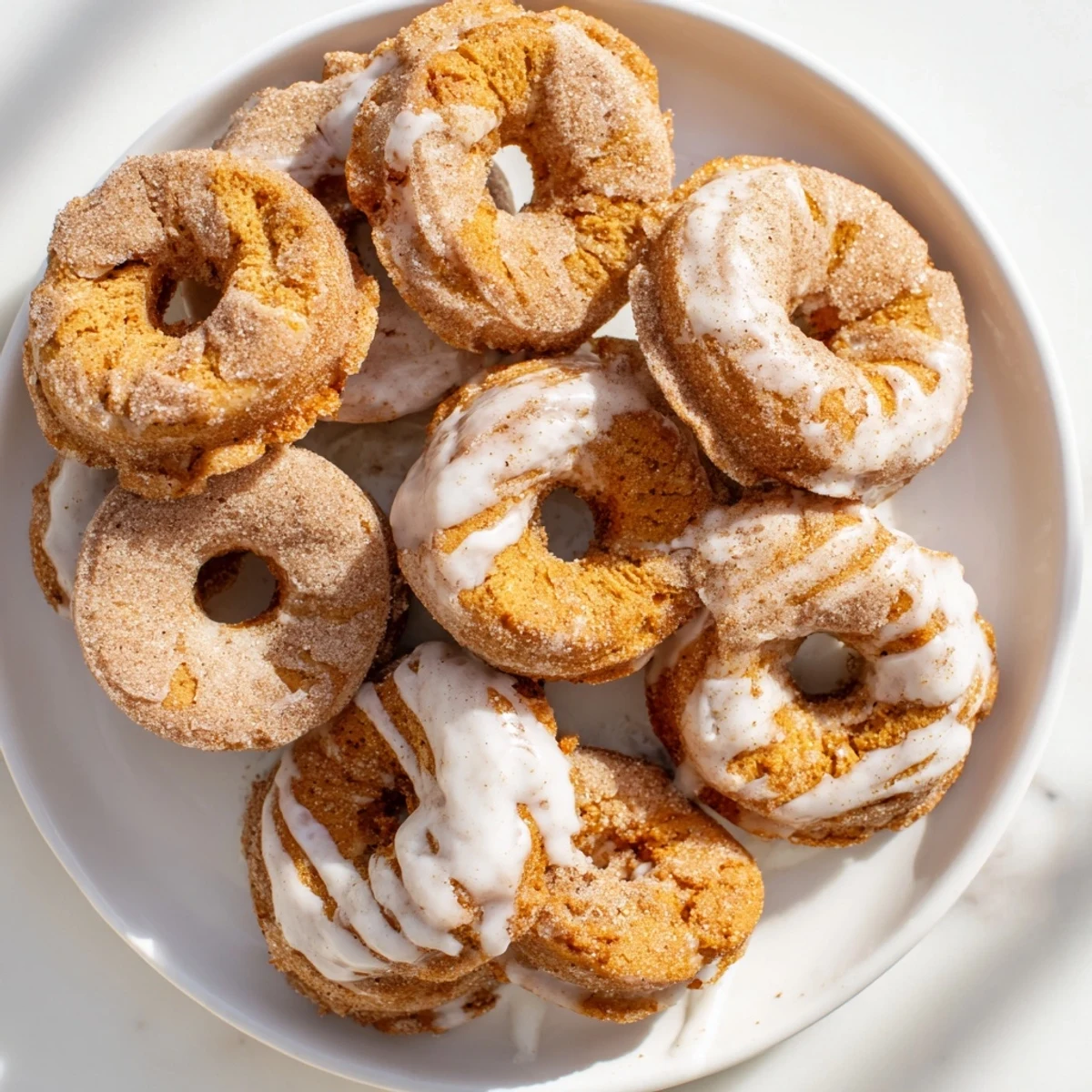 Warm pumpkin filled donuts made from biscuit dough sprinkled with spiced sugar on a white serving plate