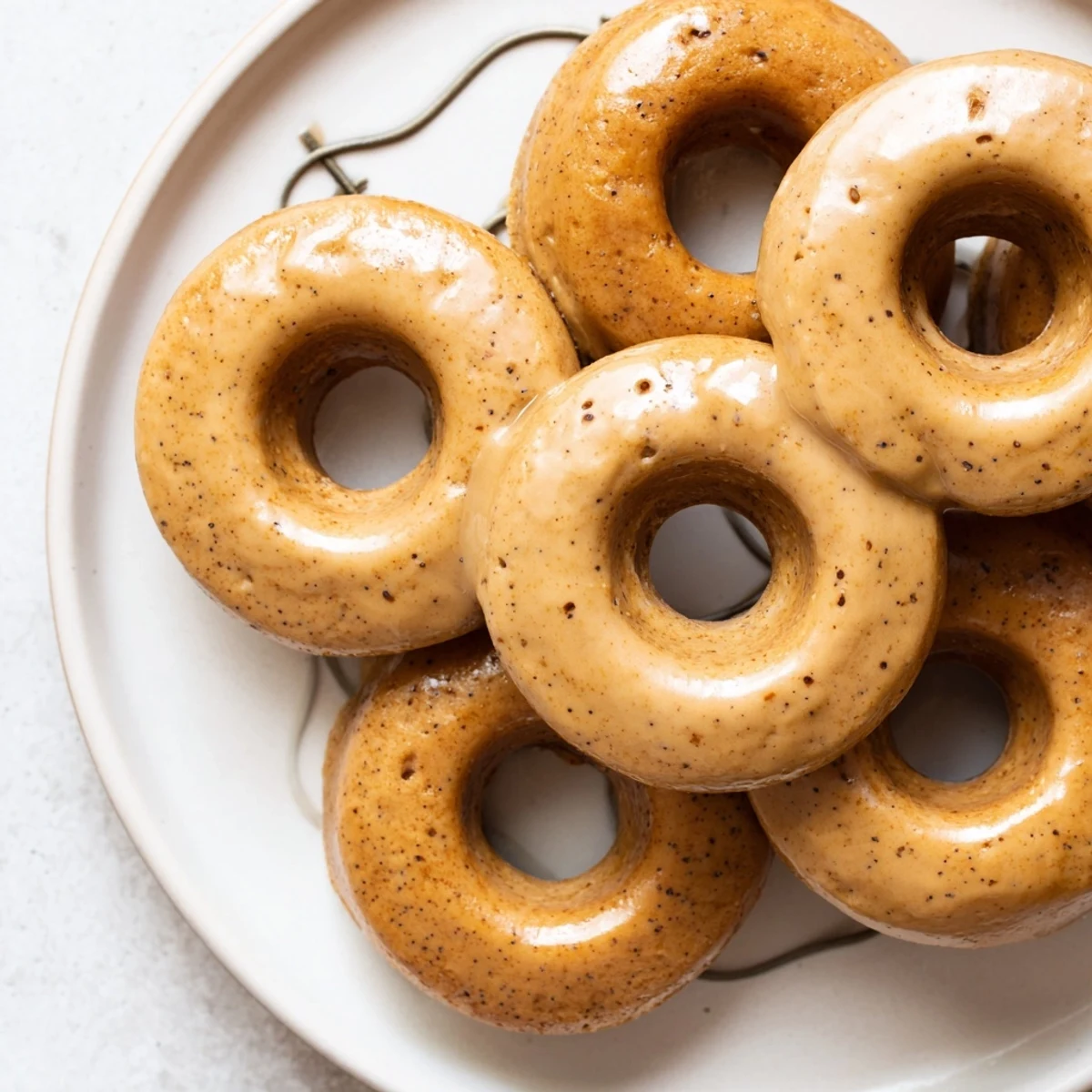 Golden brown Earl Grey mochi donuts topped with a sweet white glaze on a wire rack