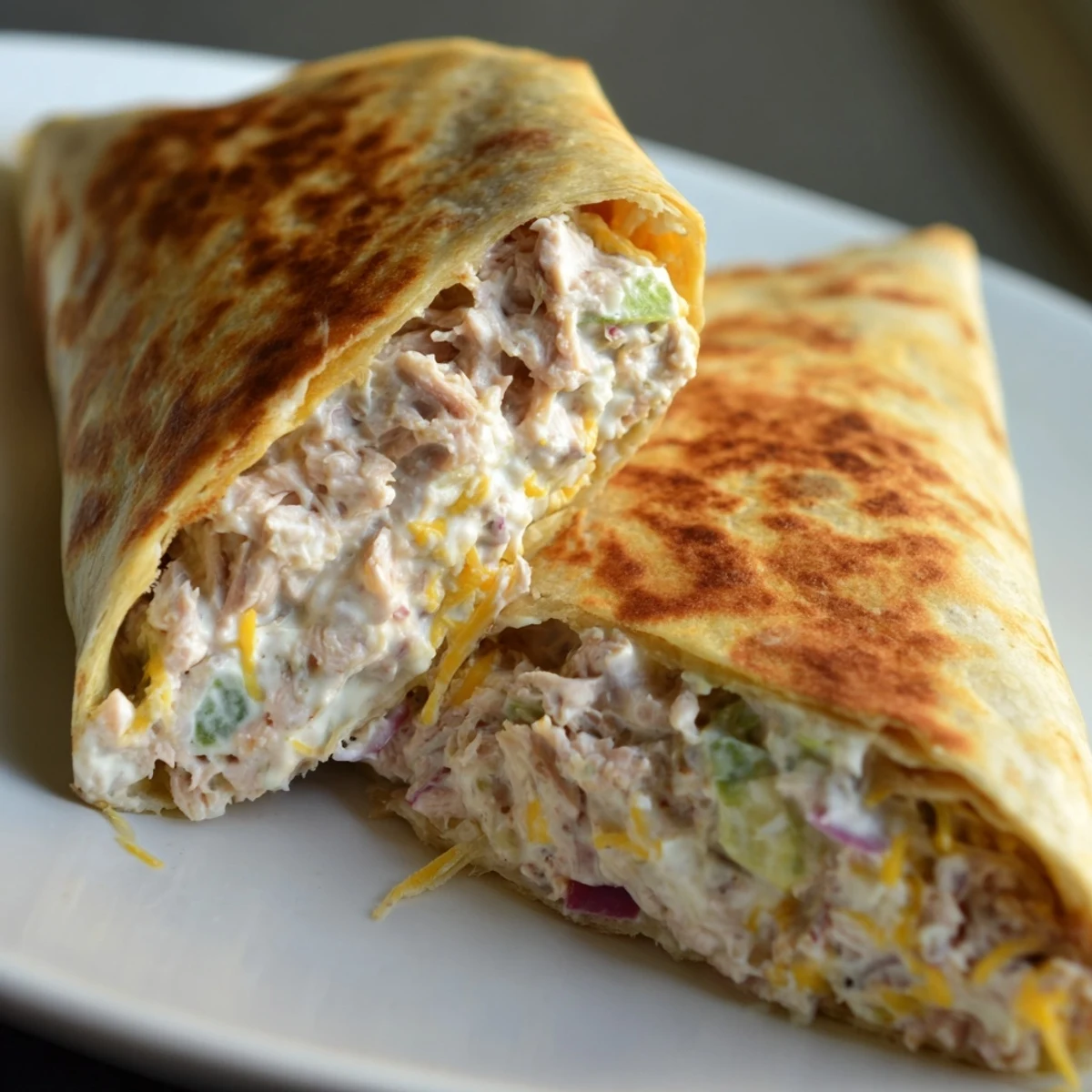 Sliced tuna melt wrap revealing creamy tuna salad filling with red onion and celery