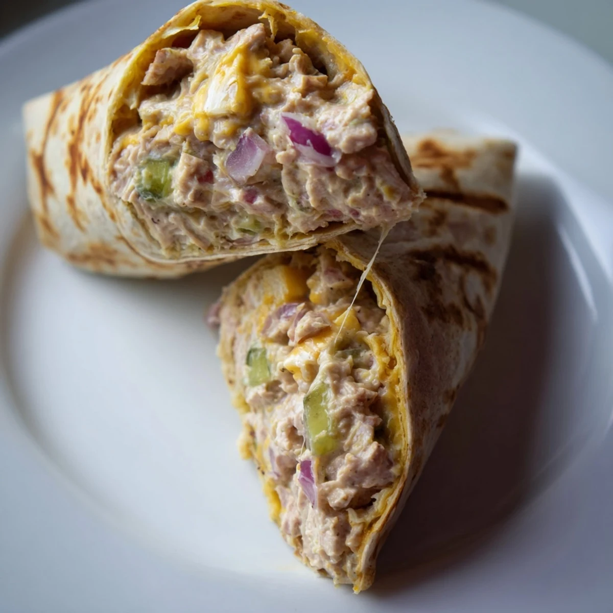 Delicious tuna melt wrap served warm on plate with visible grill marks and melted cheese