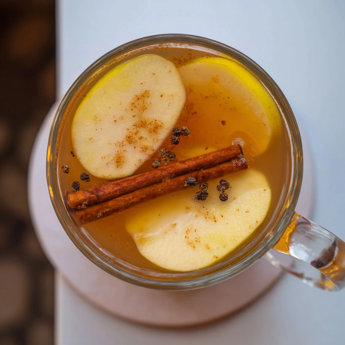 Steaming mug of homemade cinnamon pear cider garnished with fresh pear slices and cinnamon stick