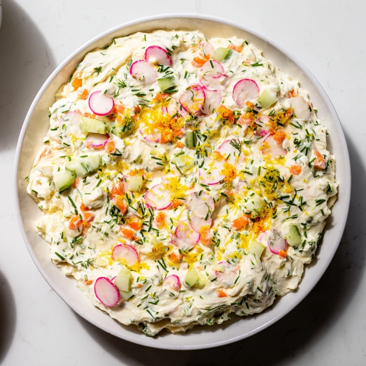 Creamy Easter dip served in a white bowl with colorful fresh vegetables and crackers surrounding it