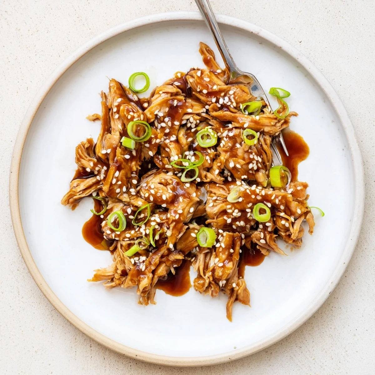Tender shredded Crockpot Teriyaki Chicken coated in thick sticky teriyaki glaze with sesame topping