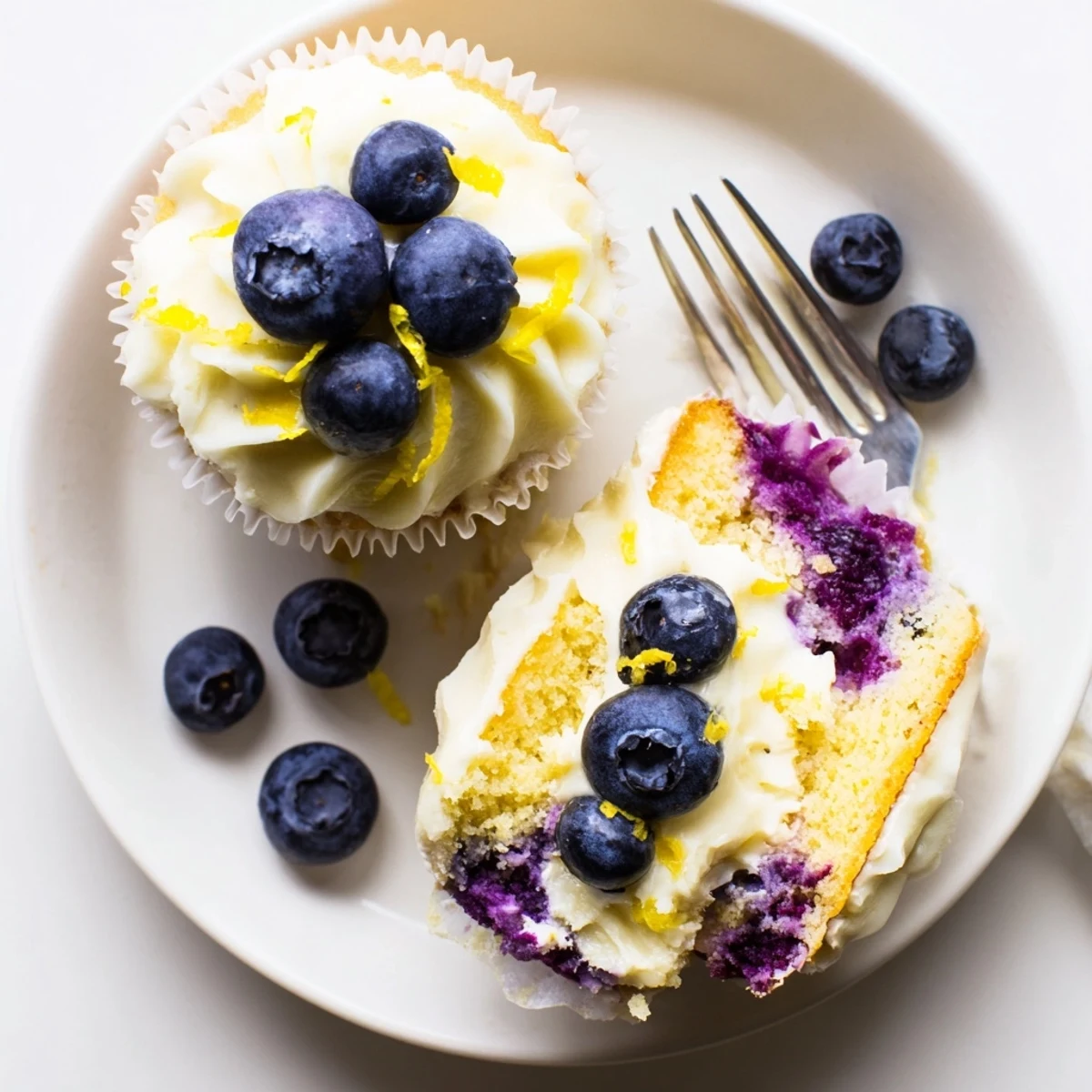 Golden homemade lemon blueberry cupcakes with swirls of tangy cream cheese frosting