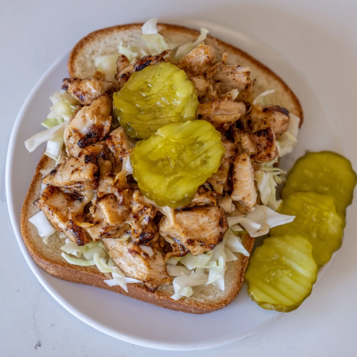 Juicy Alabama BBQ chicken chopped sandwich topped with creamy white sauce and crisp slaw on toasted bun
