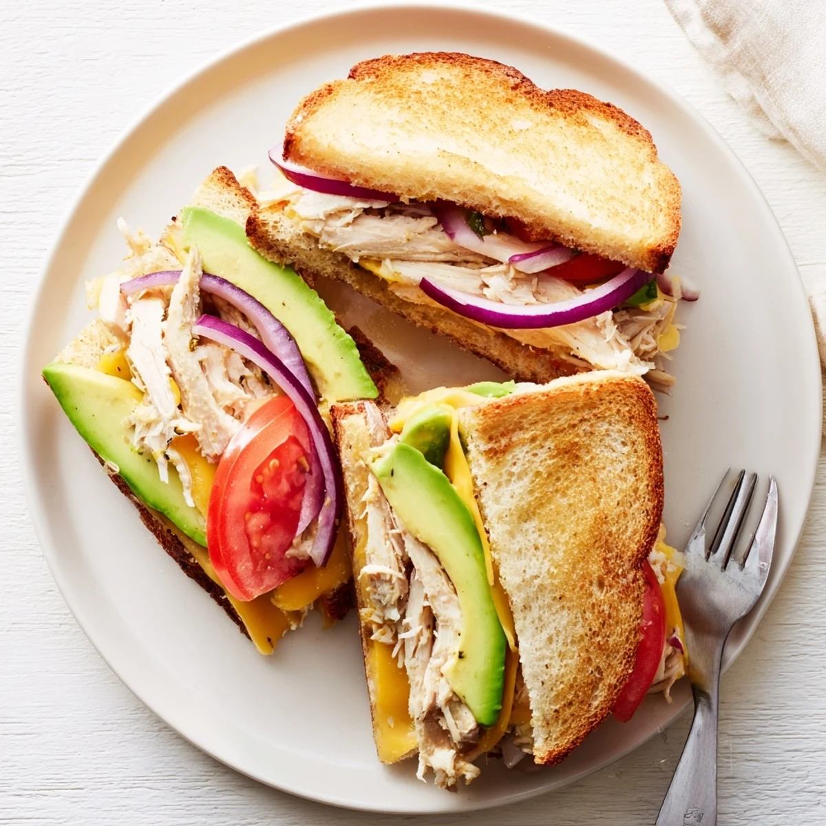 Hot chicken avocado melt sandwich cut in half revealing melted cheddar and tender shredded chicken
