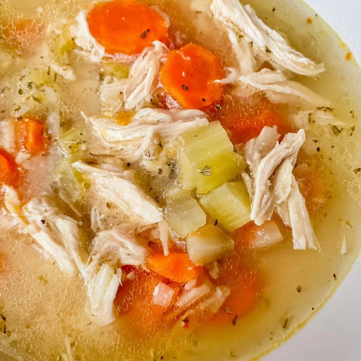 Crockpot Lemon Chicken Soup in a white bowl garnished with fresh parsley and lemon slices