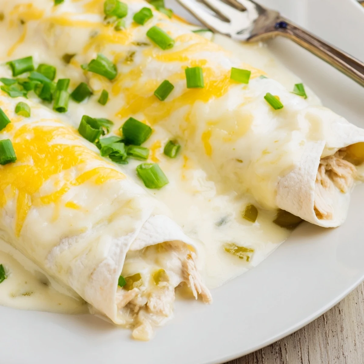Sliced Creamy White Chicken Enchiladas on baking dish, sour cream drizzle