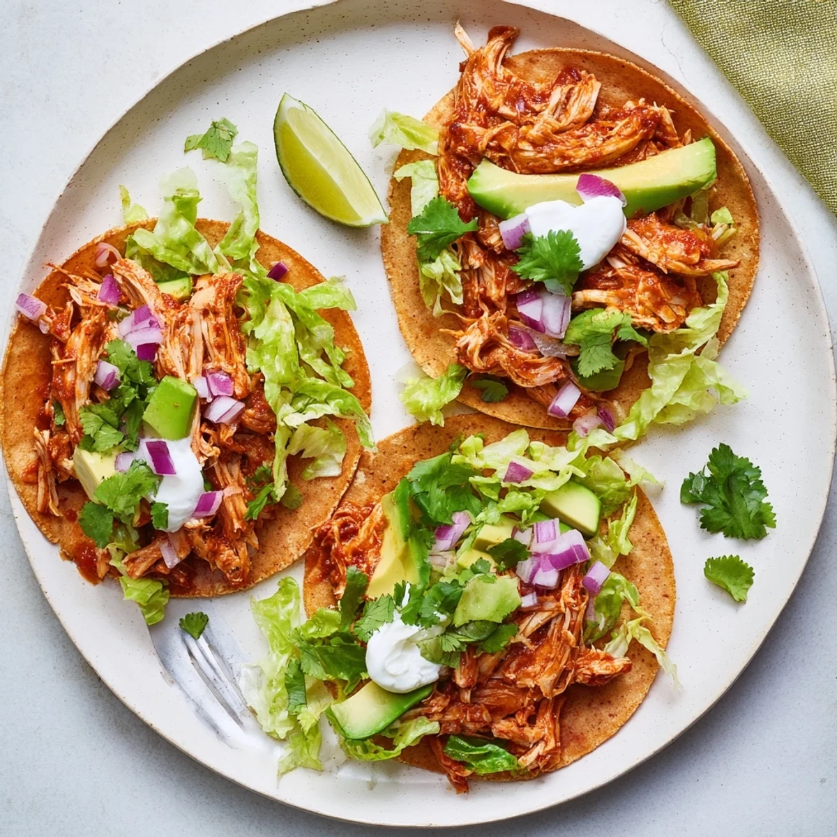 Golden shredded chicken tacos slow-cooked with Mexican spices served inside soft corn tortillas with vibrant garnishes