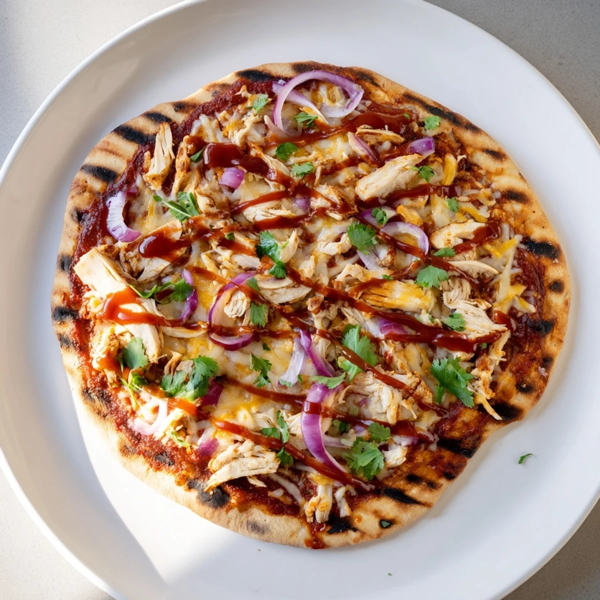 Sliced grilled chicken atop tangy BBQ sauce pizza with red onion and fresh cilantro garnish