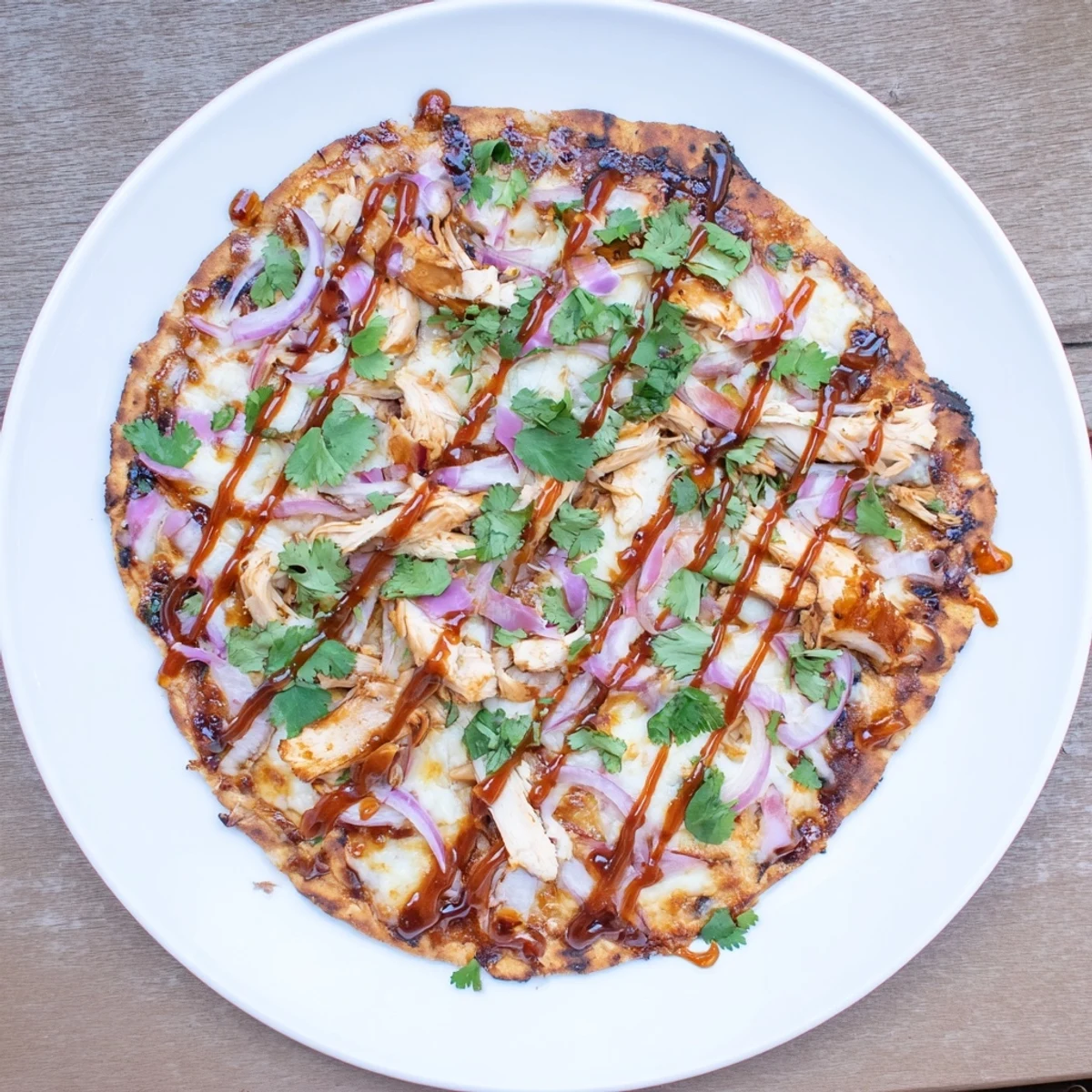 Homemade BBQ chicken pizza featuring melted cheese blend and grilled chicken on crispy grilled dough