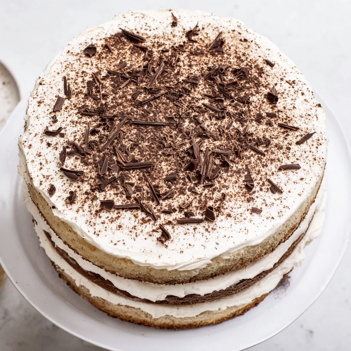 Elegant Italian tiramisu cake topped with dark chocolate shavings and a generous dusting of cocoa