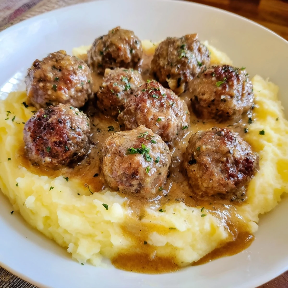 Creamy Crockpot Meatballs Gravy spooned over buttery mashed potatoes, steam gently rising