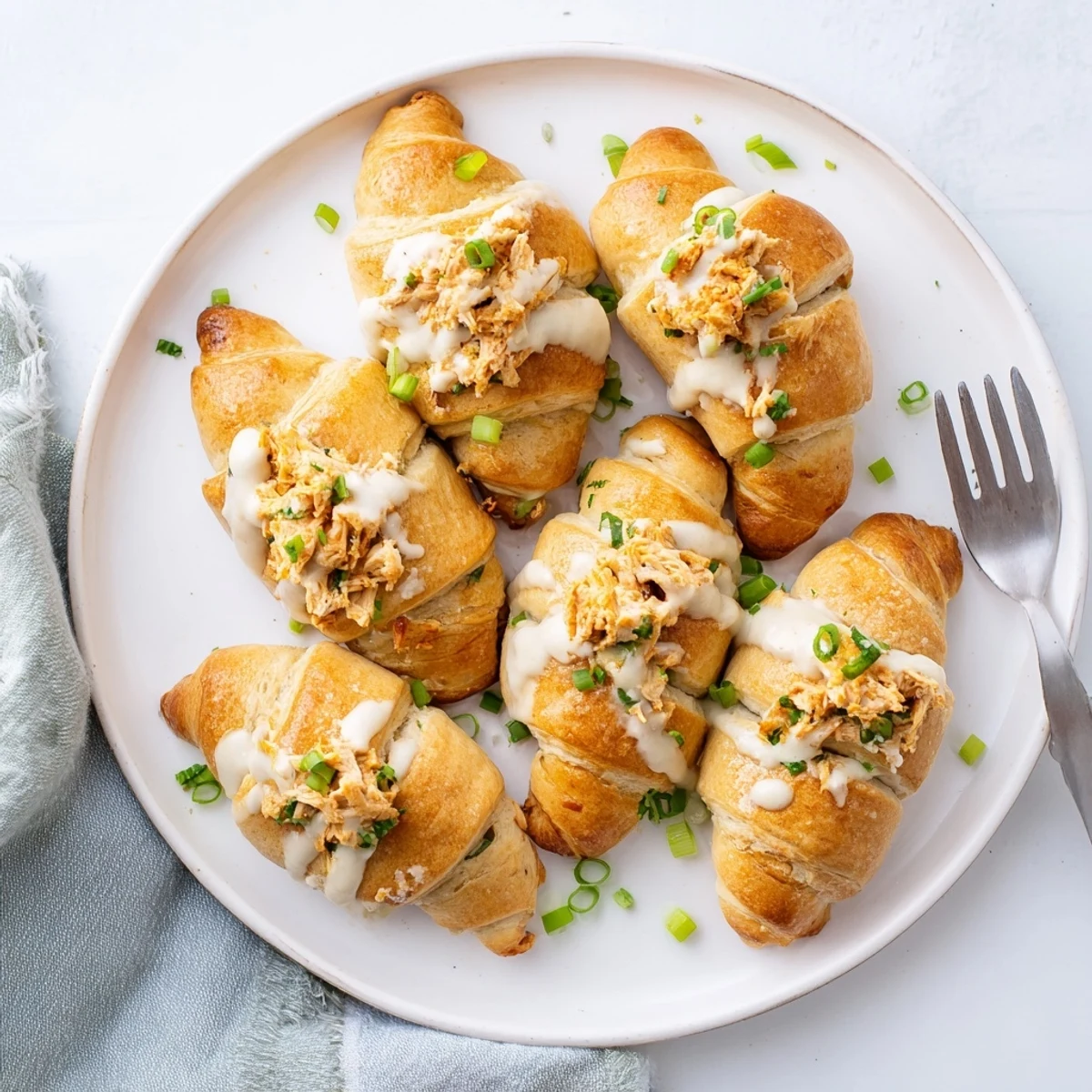 Warm chicken pillows in buttery pastry served on a plate with velvety parmesan cream sauce