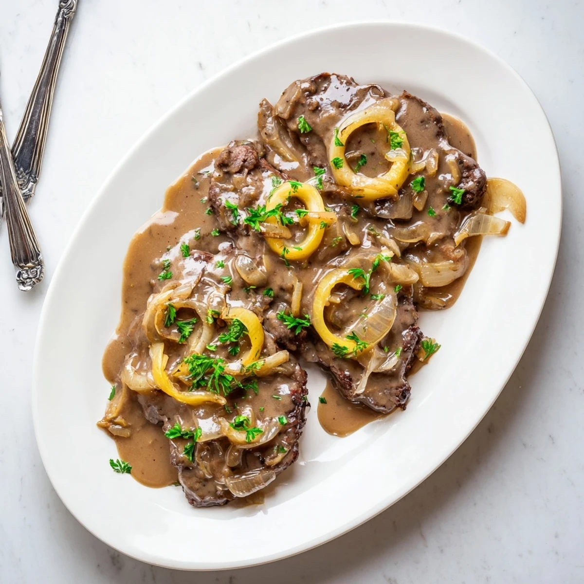 Golden brown country style smothered cube steak resting in rich onion gravy with fresh parsley garnish